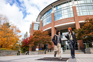 Two students walk past Belk Library on Appalachian State University’s campus during autumn.